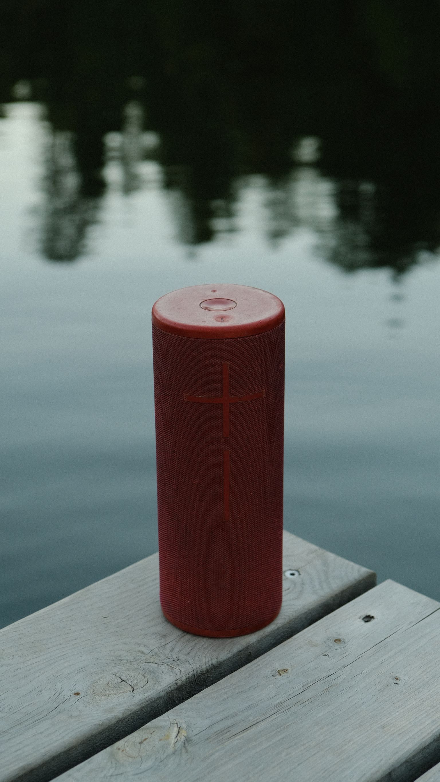 Rode draagbare bluetooth speaker op een houten steiger aan het water