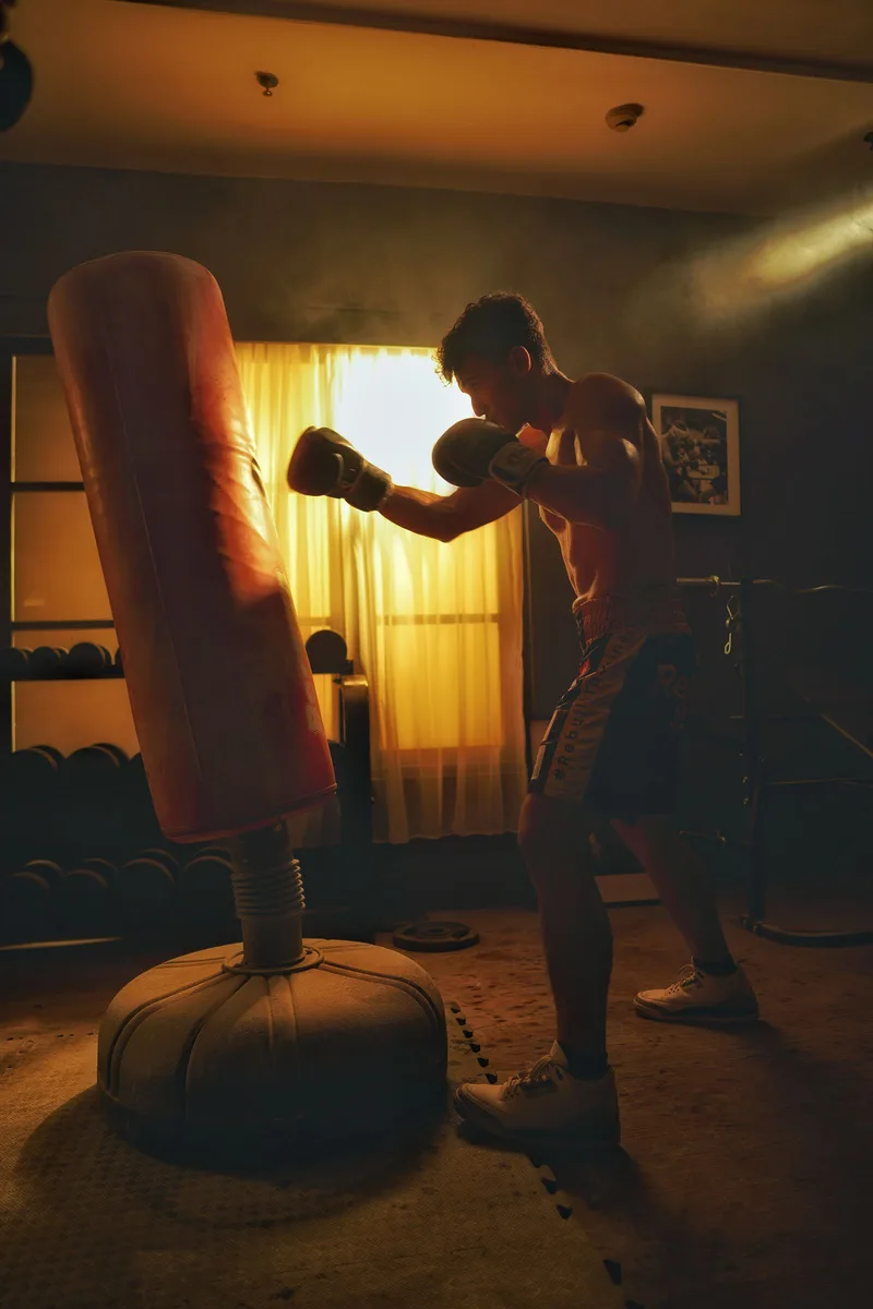 Man traint met bokshandschoenen tegen een rode staande bokszak in een thuisgym