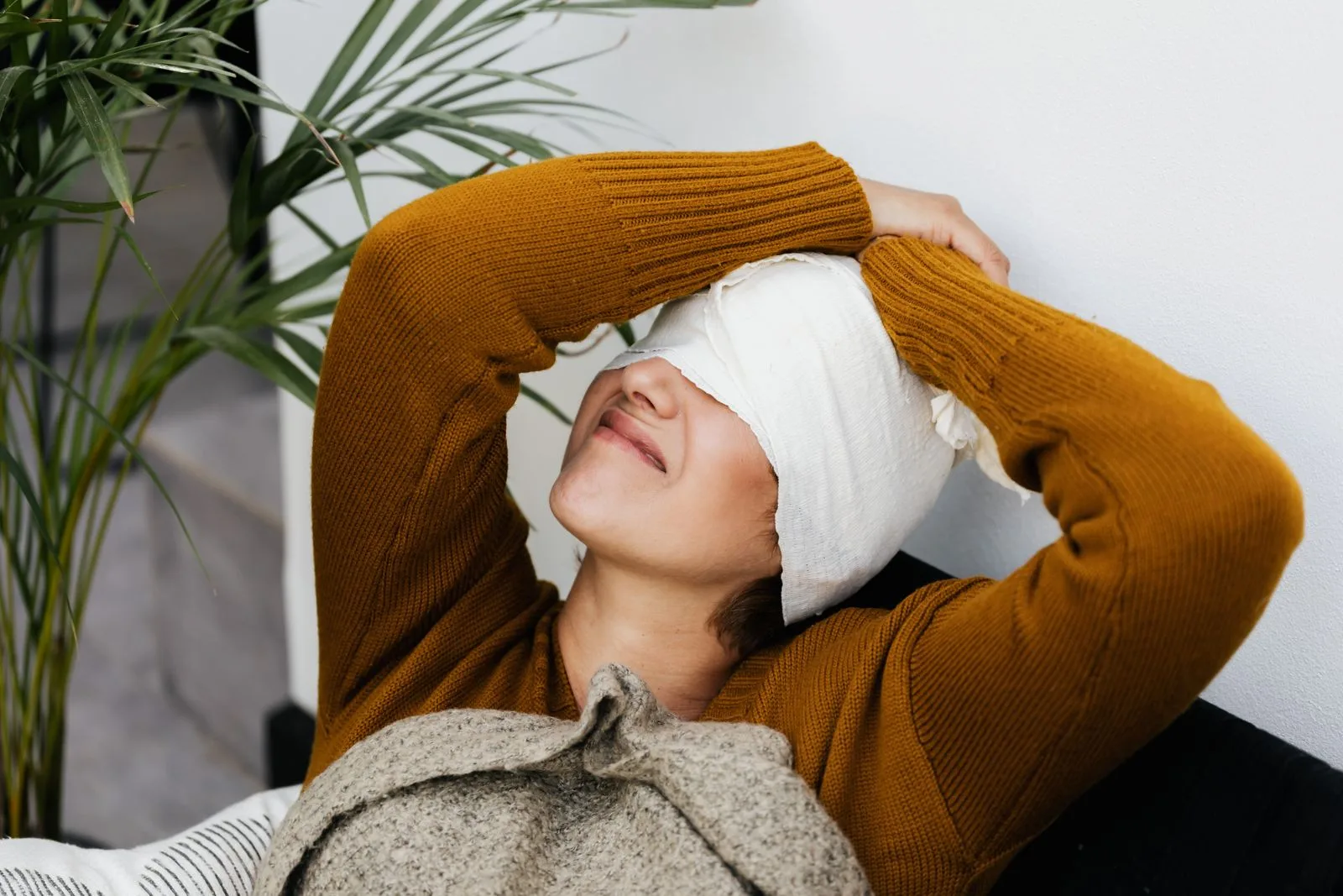 Vrouw ligt op de bank met een witte doek om haar hoofd en over haar ogen
