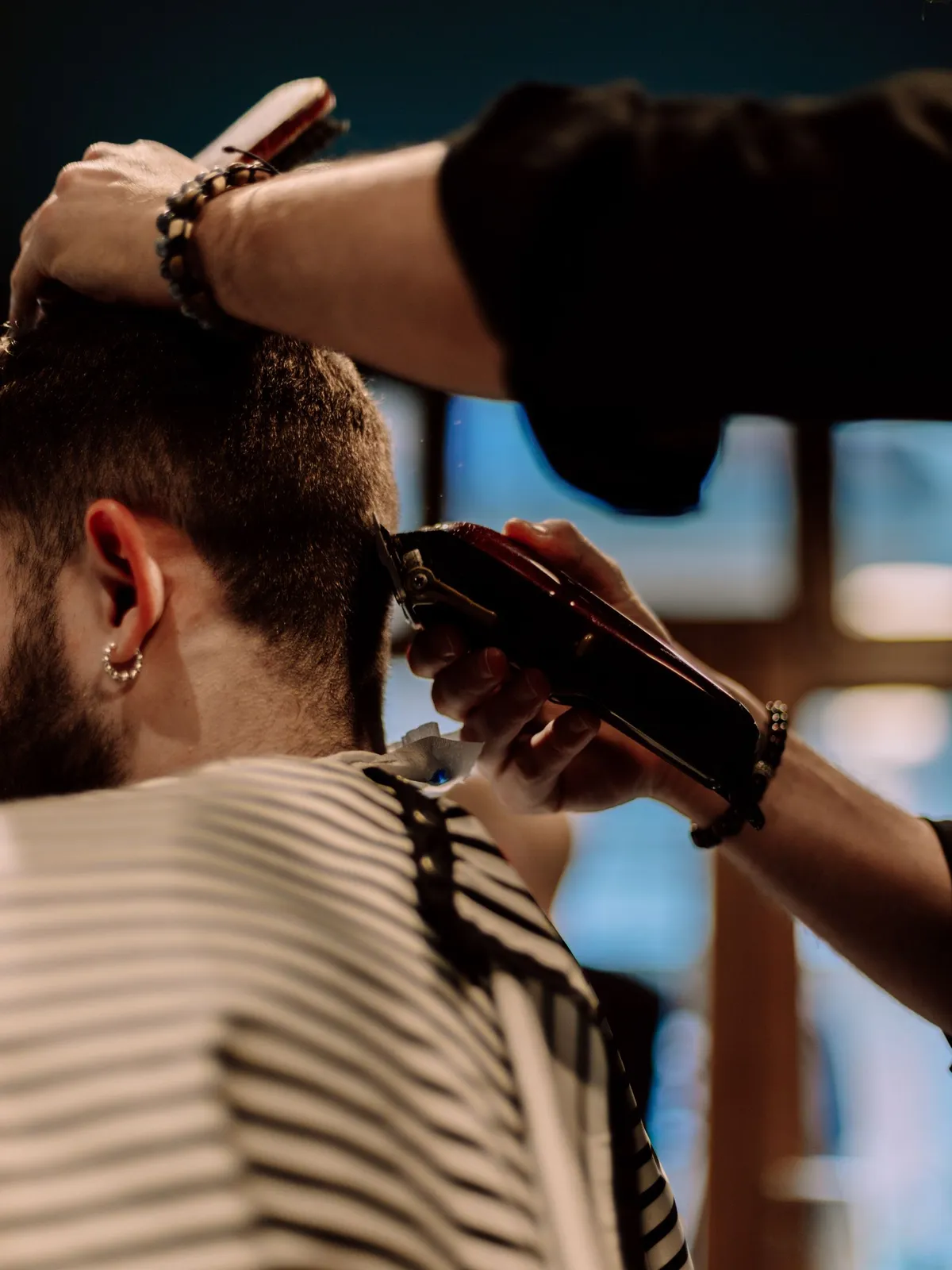 Kapper knipt de nek van een man met een tondeuse in een barbershop