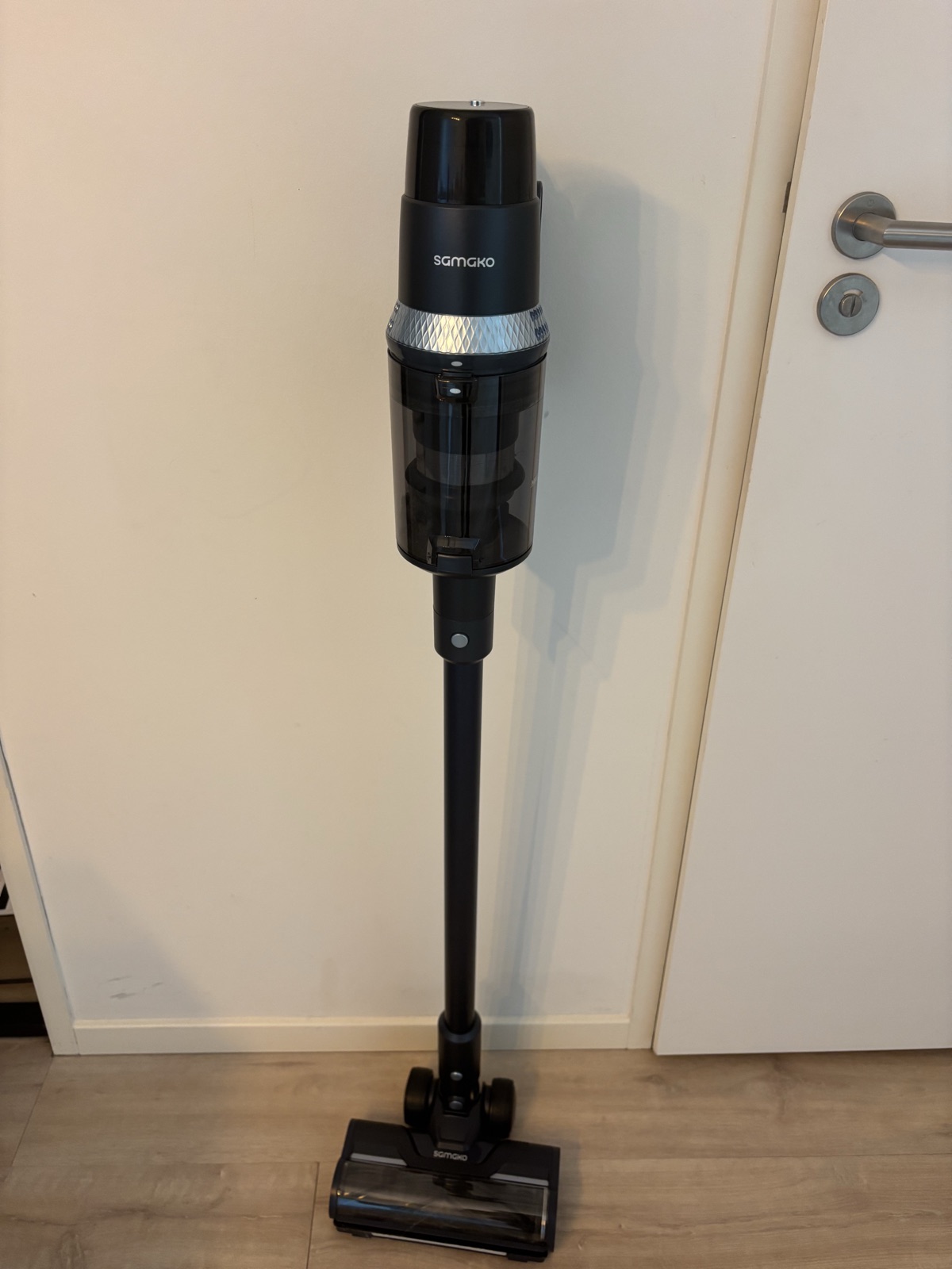 Samako CleanDetect steelstofzuiger staat rechtop tegen een witte deur op een houten vloer
