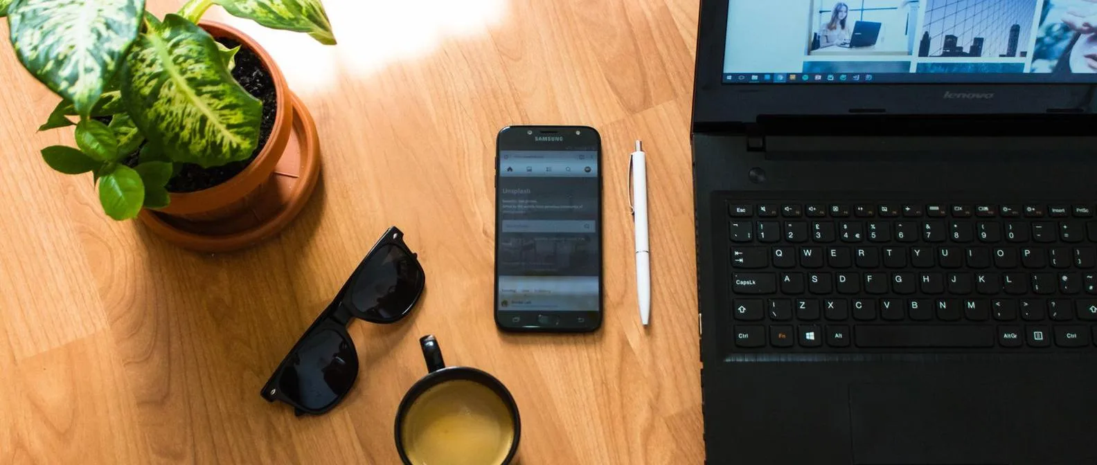 Houten bureau met laptop, telefoon, koffie en een plant, klaar om producten te vergelijken