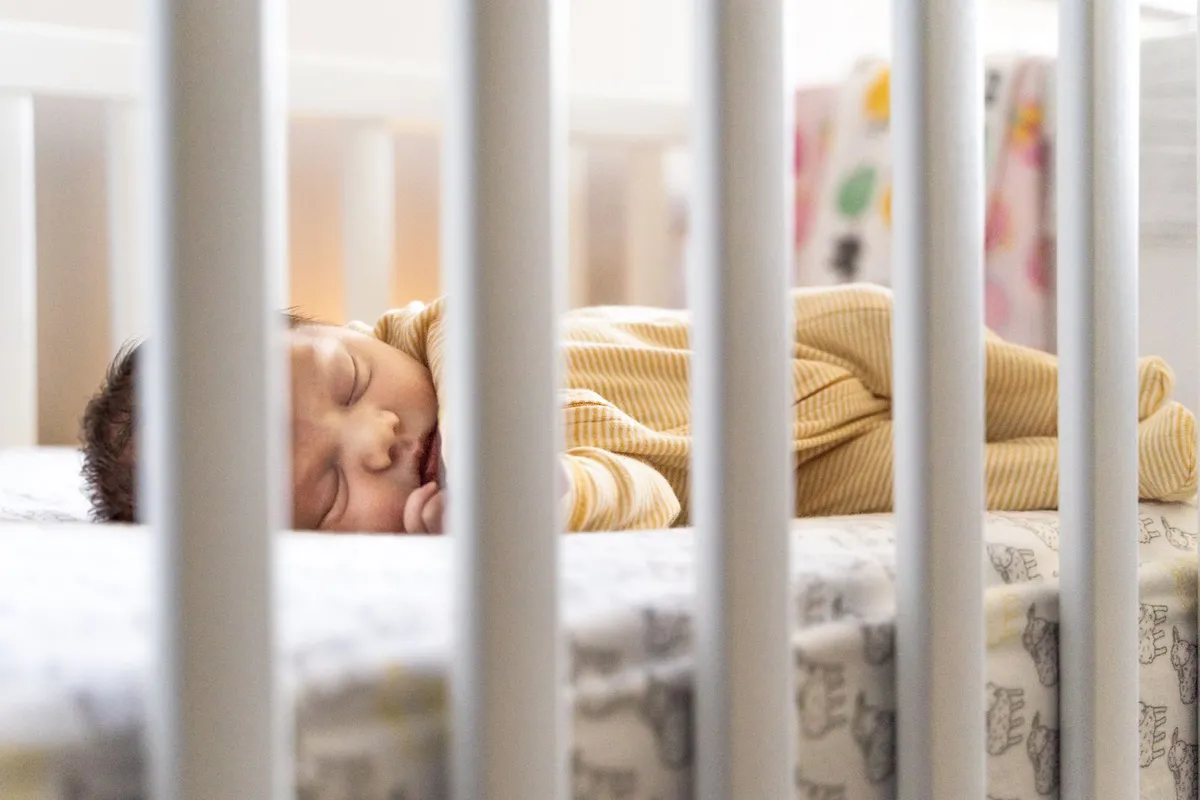 Baby slaapt rustig in een wit ledikantje