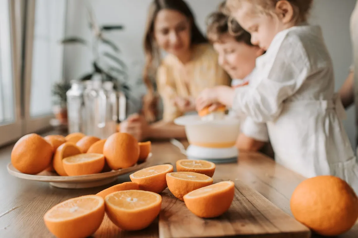 Gezin perst samen sinaasappels met een citruspers aan de keukentafel