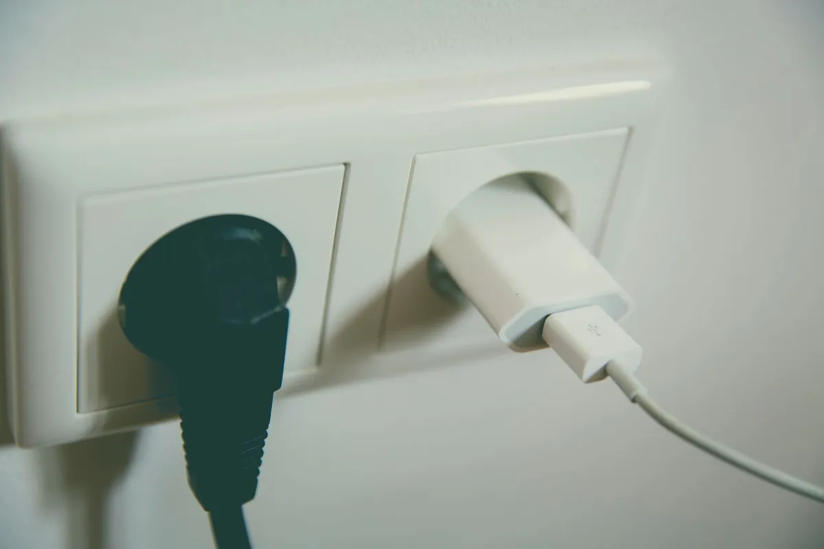 Twee stekkers in een wit dubbel stopcontact aan de muur