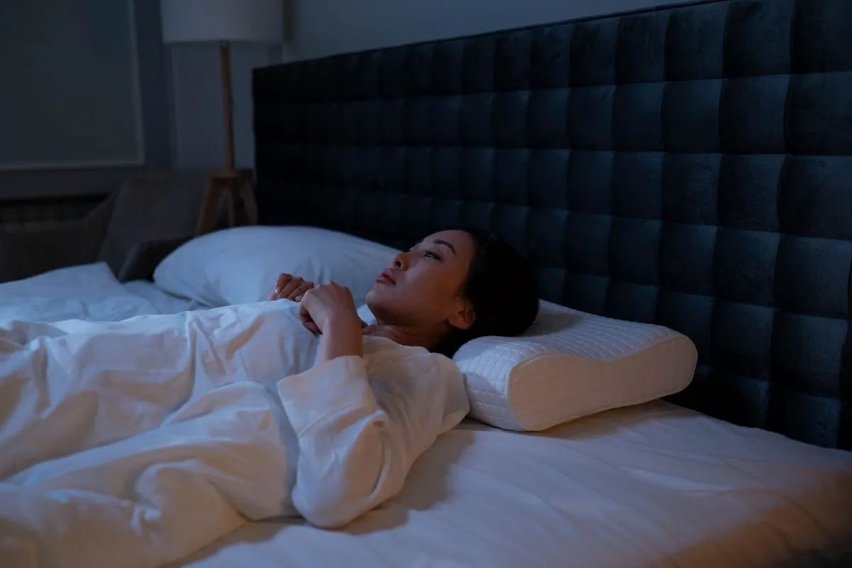 Vrouw slaapt op haar rug met haar nek ondersteund door een contour memory foam kussen
