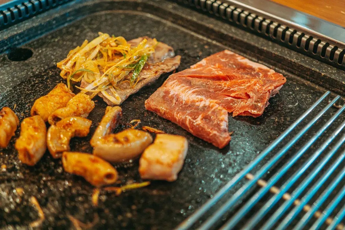 Vlees, inktvis en groenten garen op een hete grillplaat aan tafel