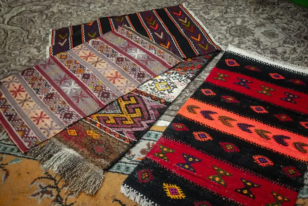 Handgeweven kelims met kleurrijke motieven en franjes liggen op een groter vloerkleed