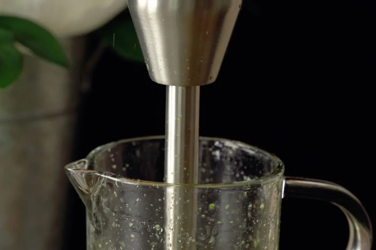 Rvs staafmixer met de mixervoet in een glazen maatbeker