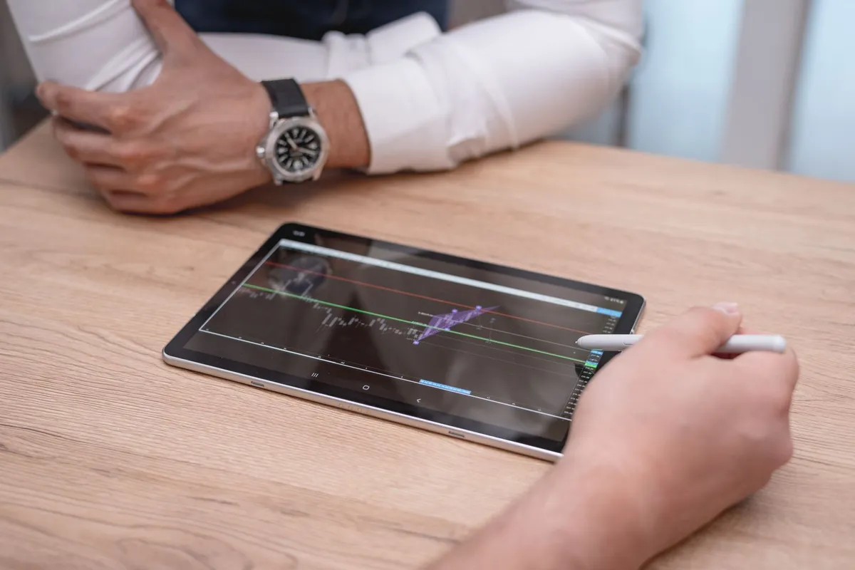 Hand met stylus werkt op een tablet die plat op een houten tafel ligt