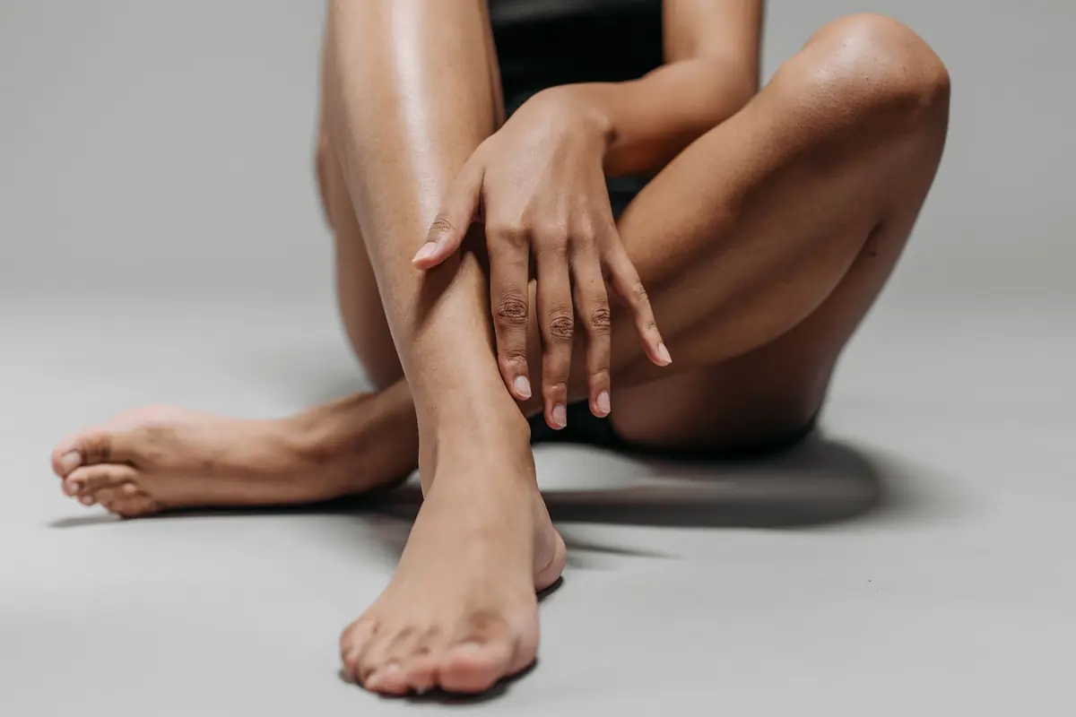Vrouw zit op de grond met haar hand op haar gladde, blote benen