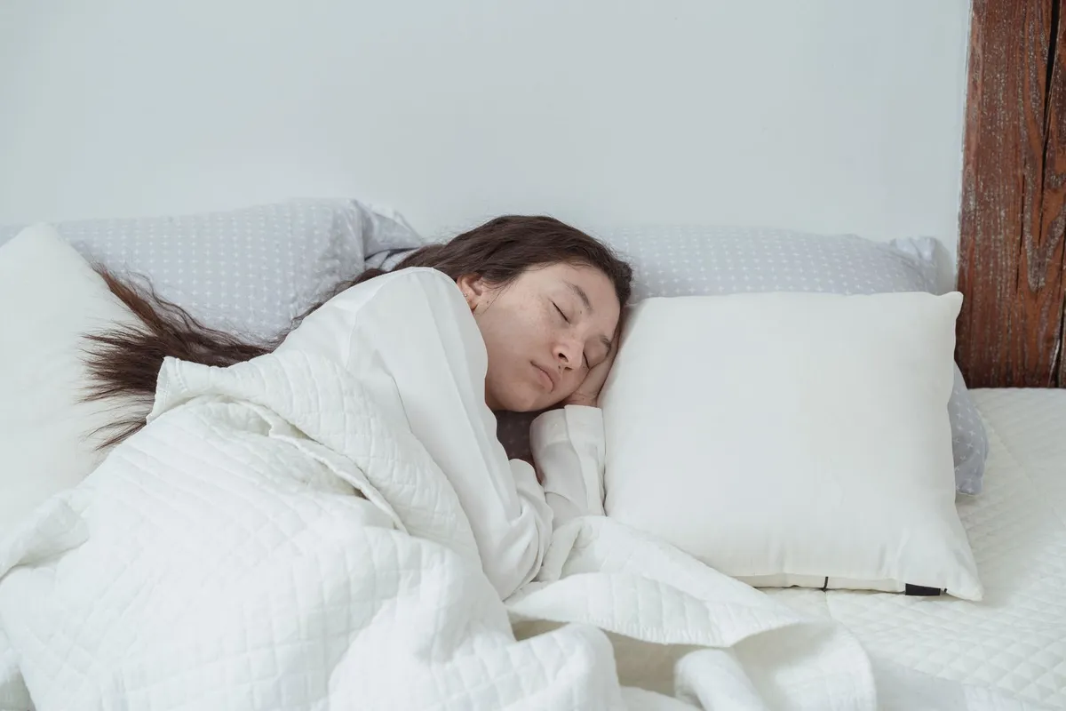 Vrouw slaapt rustig op haar zij in een wit opgemaakt bed